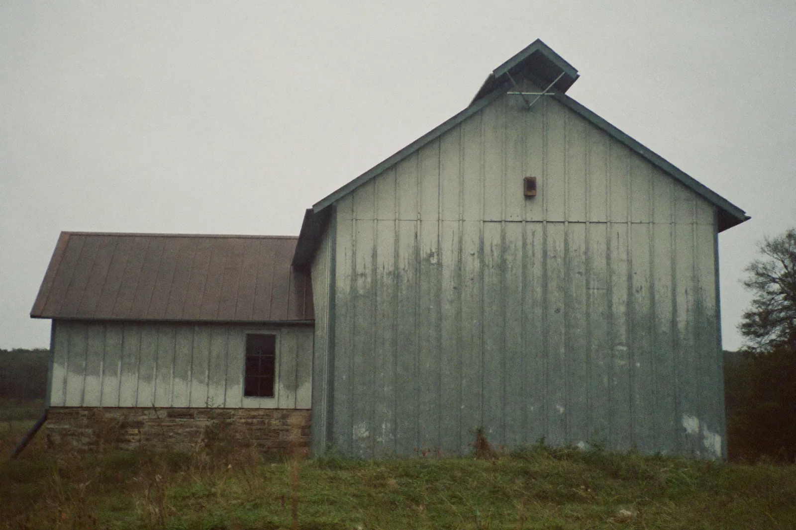 An old wooden bank barn with a stone foundation, still standing in a Pennsylvania field
