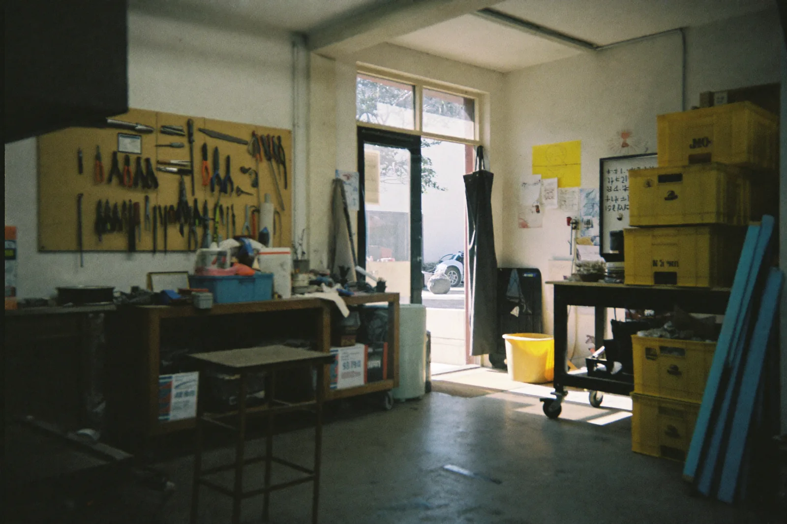 The inside of a small workshop before opening, tools on the wall and daylight through the front window
